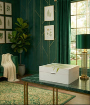 Decorative interior with green walls, a white box on a table, and framed botanical prints.