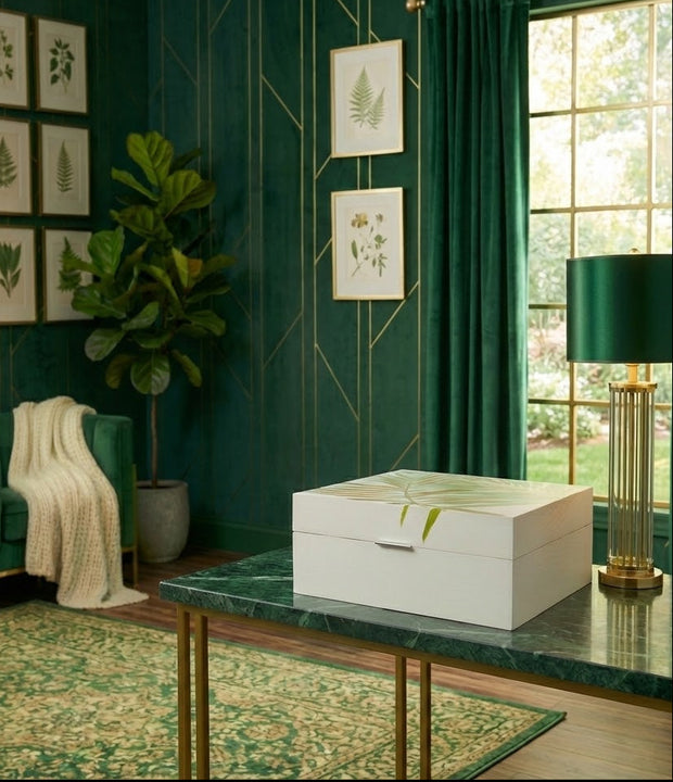 Decorative interior with green walls, a white box on a table, and framed botanical prints.