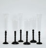 Set of six clear glass candle holders with black twisted bases on a white background