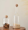 Two glass jars with wooden lids on a wooden surface against a light background