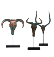 Three bronze animal head sculptures with large horns on black stands against a white background