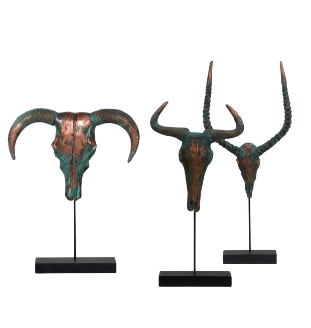 Three bronze animal head sculptures with large horns on black stands against a white background