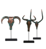 Three bronze animal head sculptures with large horns on black stands against a white background